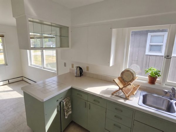 Kitchen cabinets after refinishing, sage green lowers and white walls