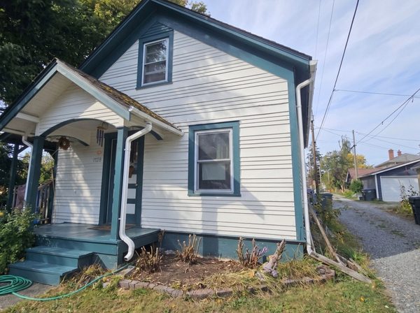 Heritage cottage exterior after repainting, fresh white siding and deep teal trim